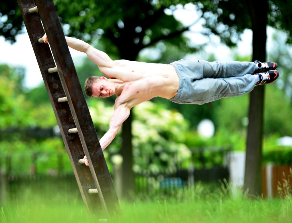 Парень делает «флажок» — боковой баланс, базовый статический элемент силовой гимнастики