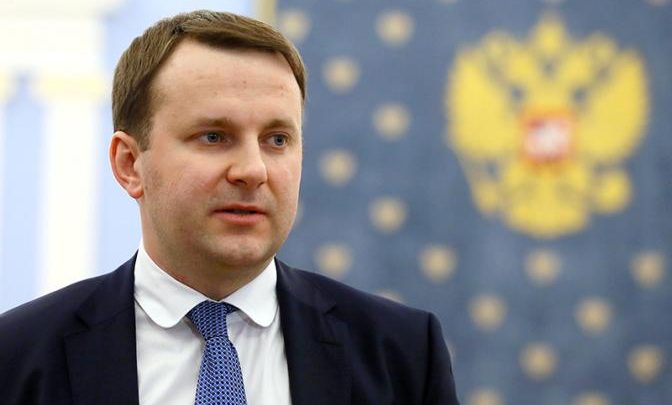 Максим Орешкин Минэконом развития России на фоне Российского Герба