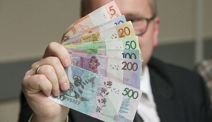 Человек держит в руке различные купюры Белорусского образца