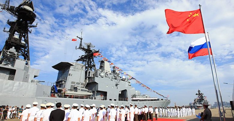 Моряки из Росссии и Китая на фоне военного корадля и флагов двух стран
