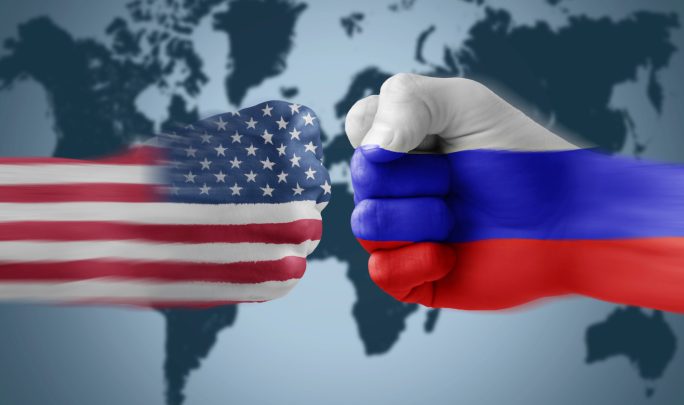 Кулаки раскрашенные во флаги США и России на фоне карты мира