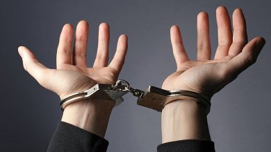Руки в наручниках на сером фоне