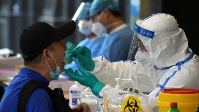 Медик в защитном костюме берет мазок на коронавирус у пациента